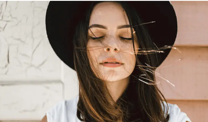 A woman wearing a hat with her eyes closed, exploring the benefits of 5 herbs for mental health.