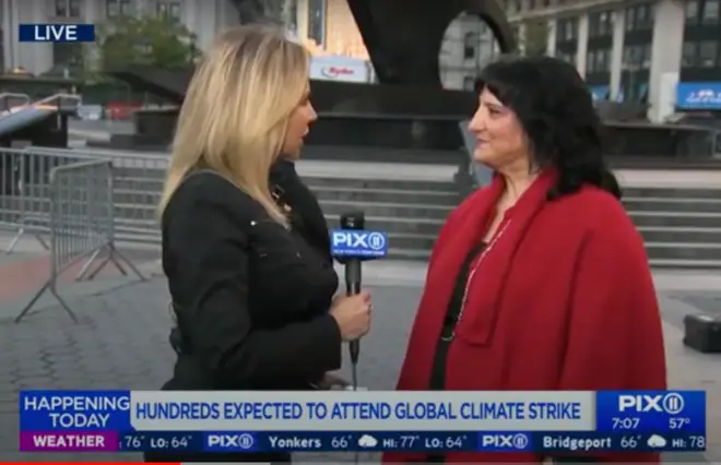 A woman in a red coat is talking to a news reporter for a media interview.