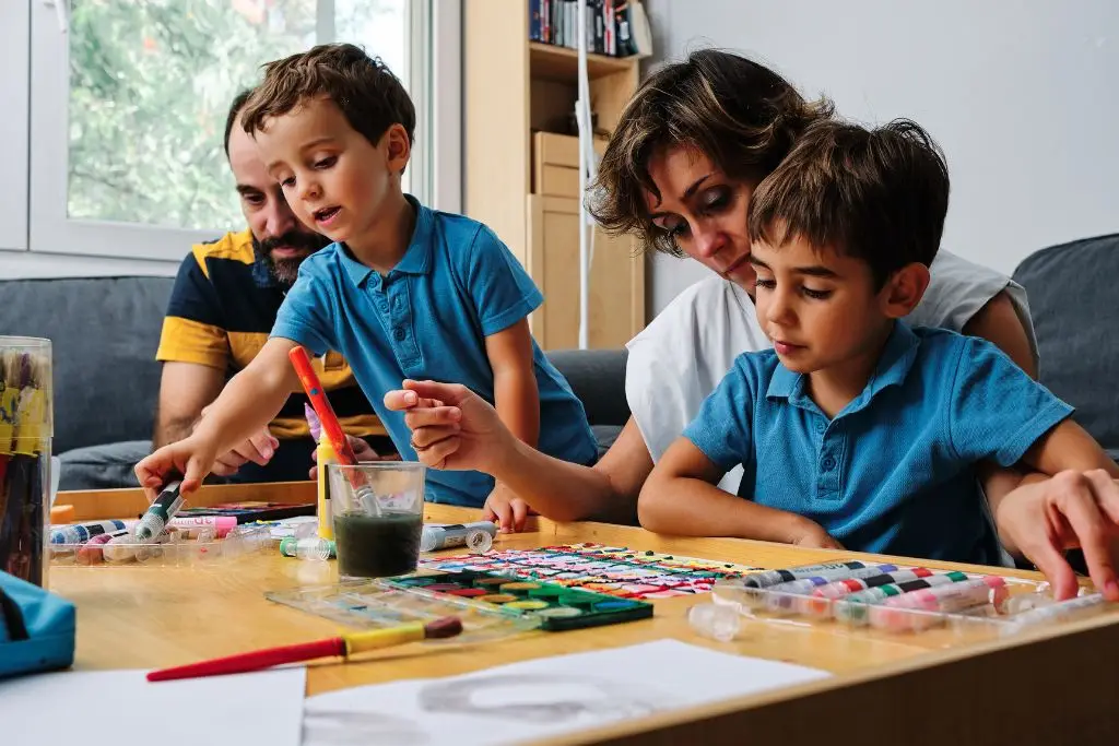 Two children sitting with their mom and dad, all reading together on a couch, sharing a quiet family bonding moment through books.